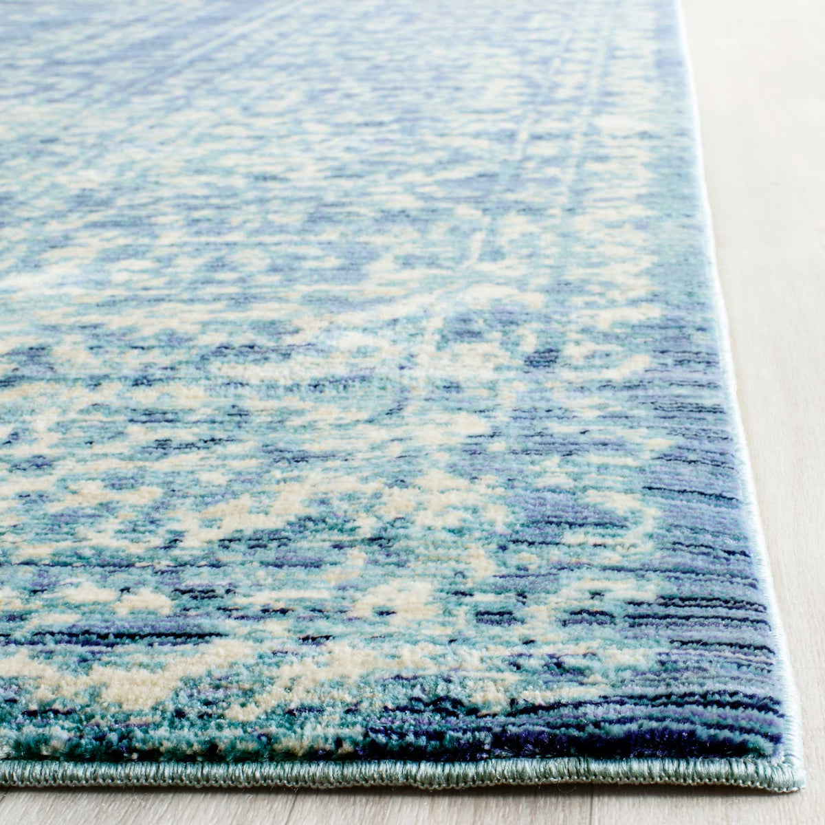 A neatly bound edge finishes the rug's textured blue and cream pattern.