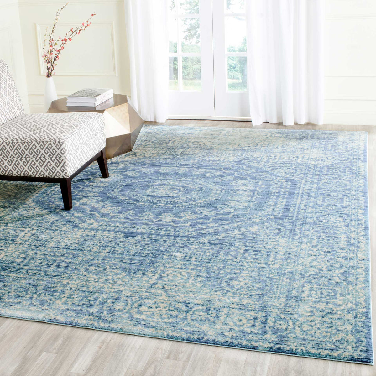 A softly faded blue medallion rug adds classic pattern to a bright bedroom.