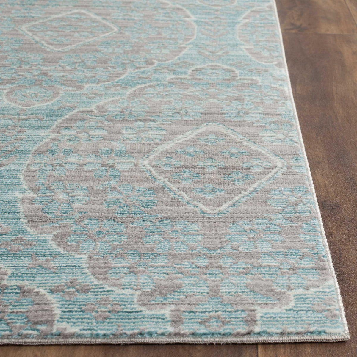 A low, textured pile brings out the rug's aqua accents, diamond motif, and bound edge.
