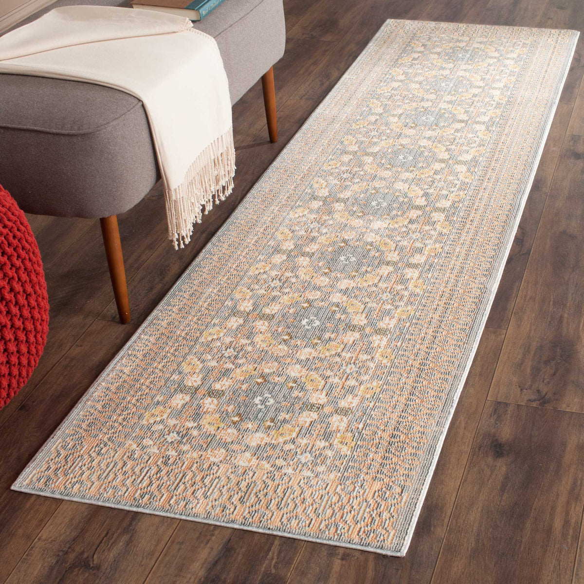 A softly distressed gray and peach runner adds warmth beside a sofa