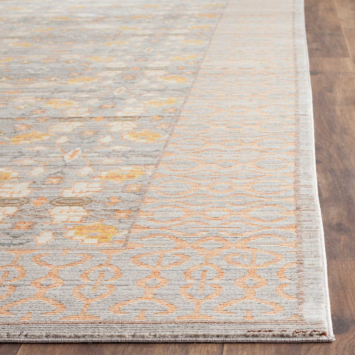 Bound rug edges frame light gray and peach ornamental detailing