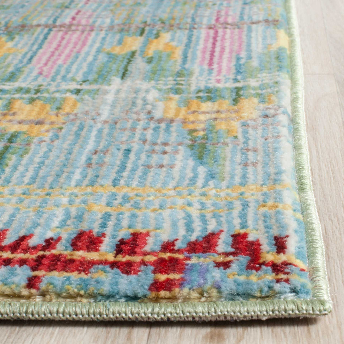 A neatly bound edge frames light blue polyester pile with vibrant red and gold accents.