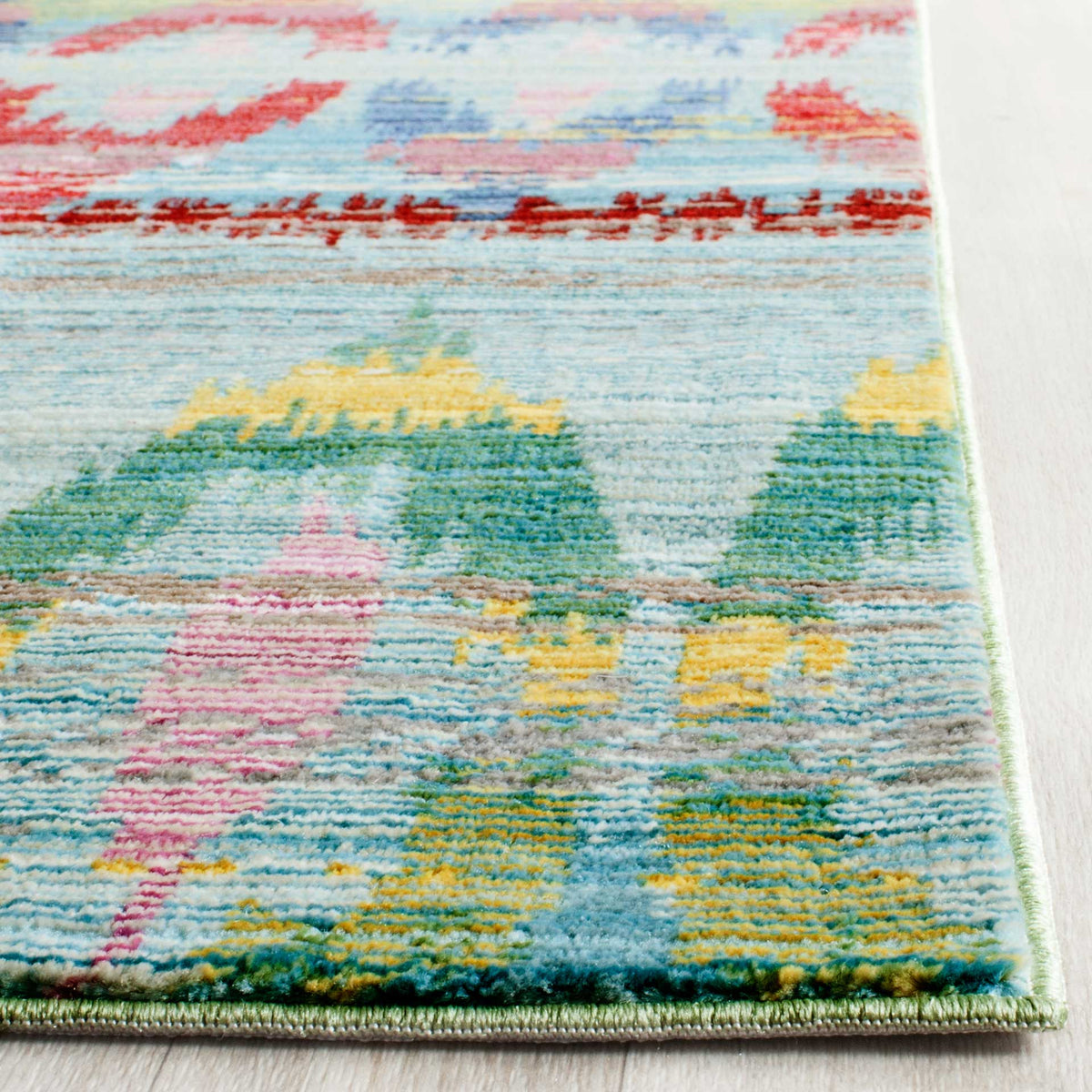 Pink, yellow, and green motifs mingle with light blue pile along a neatly bound edge.