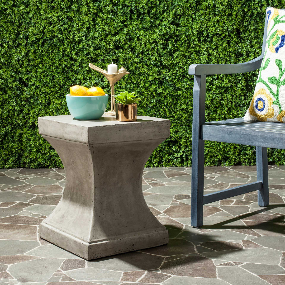 A dark gray concrete side table offers a sturdy square surface for outdoor seating.