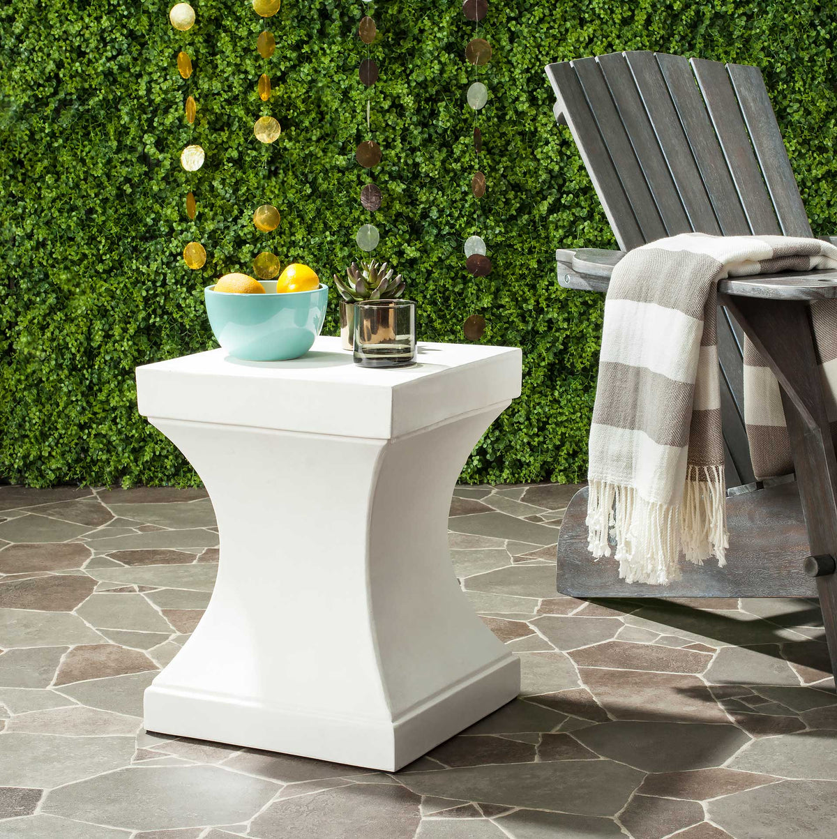 An ivory concrete side table adds a handy square surface beside an outdoor chair.