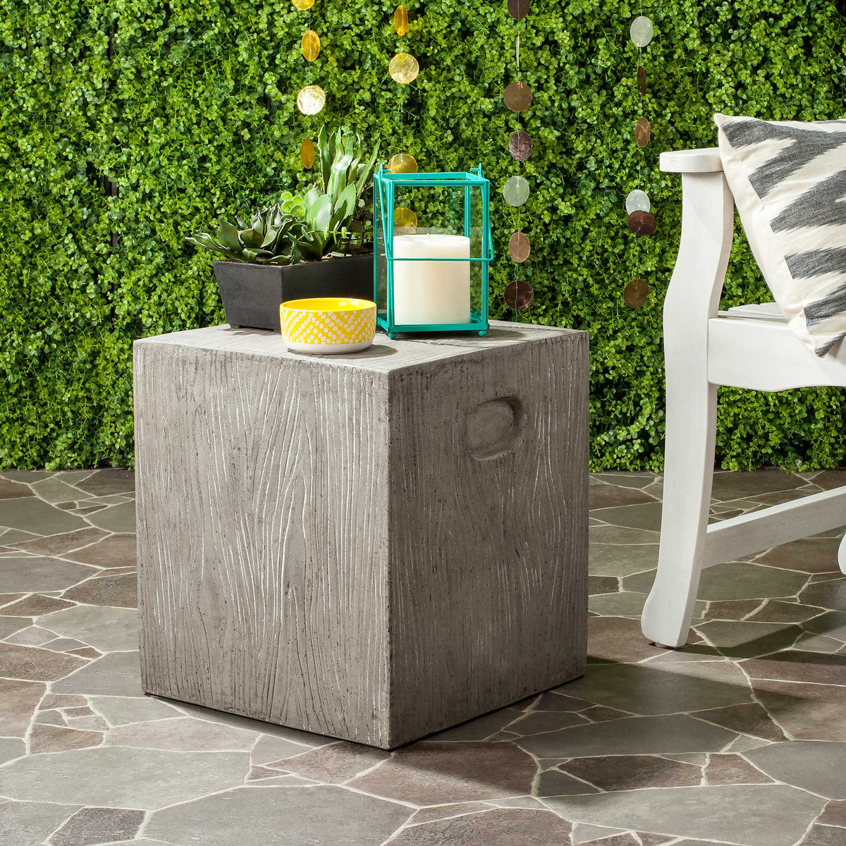A dark gray cube table brings wood-grain texture and a recessed grip to an outdoor seating area.