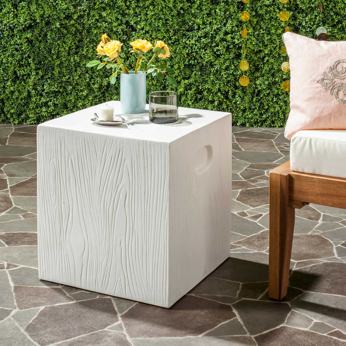 An ivory cube table adds textured concrete and a recessed grip beside outdoor seating.