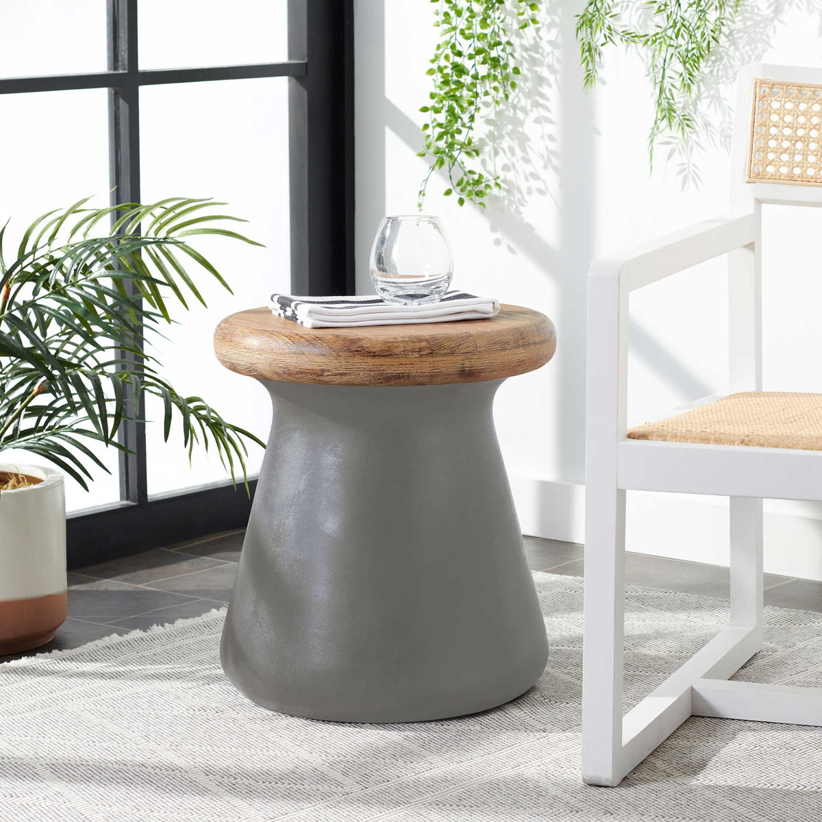 Dark gray concrete table with a natural wood top holds a small vase and reading material