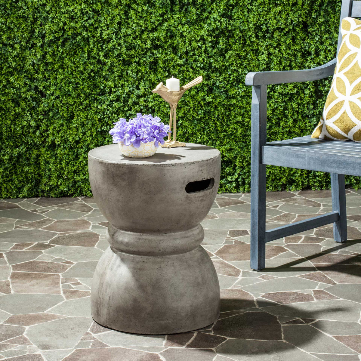Dark gray concrete accent table offers a handy surface for outdoor drinks and flowers