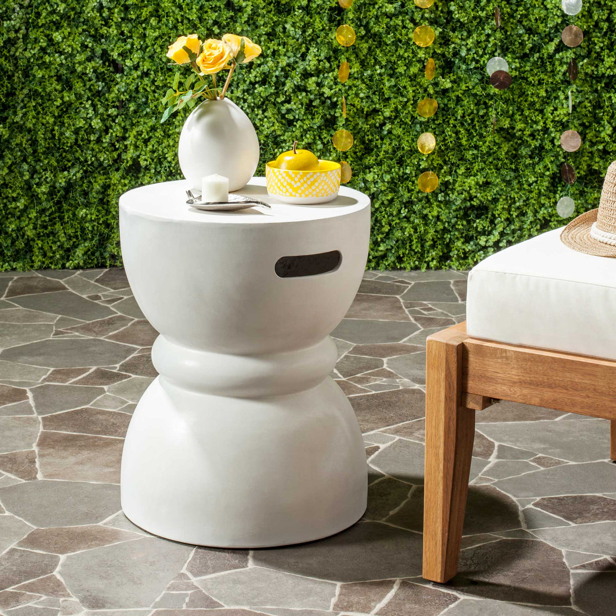 Ivory concrete accent table provides a sculptural perch for flowers and refreshments outdoors