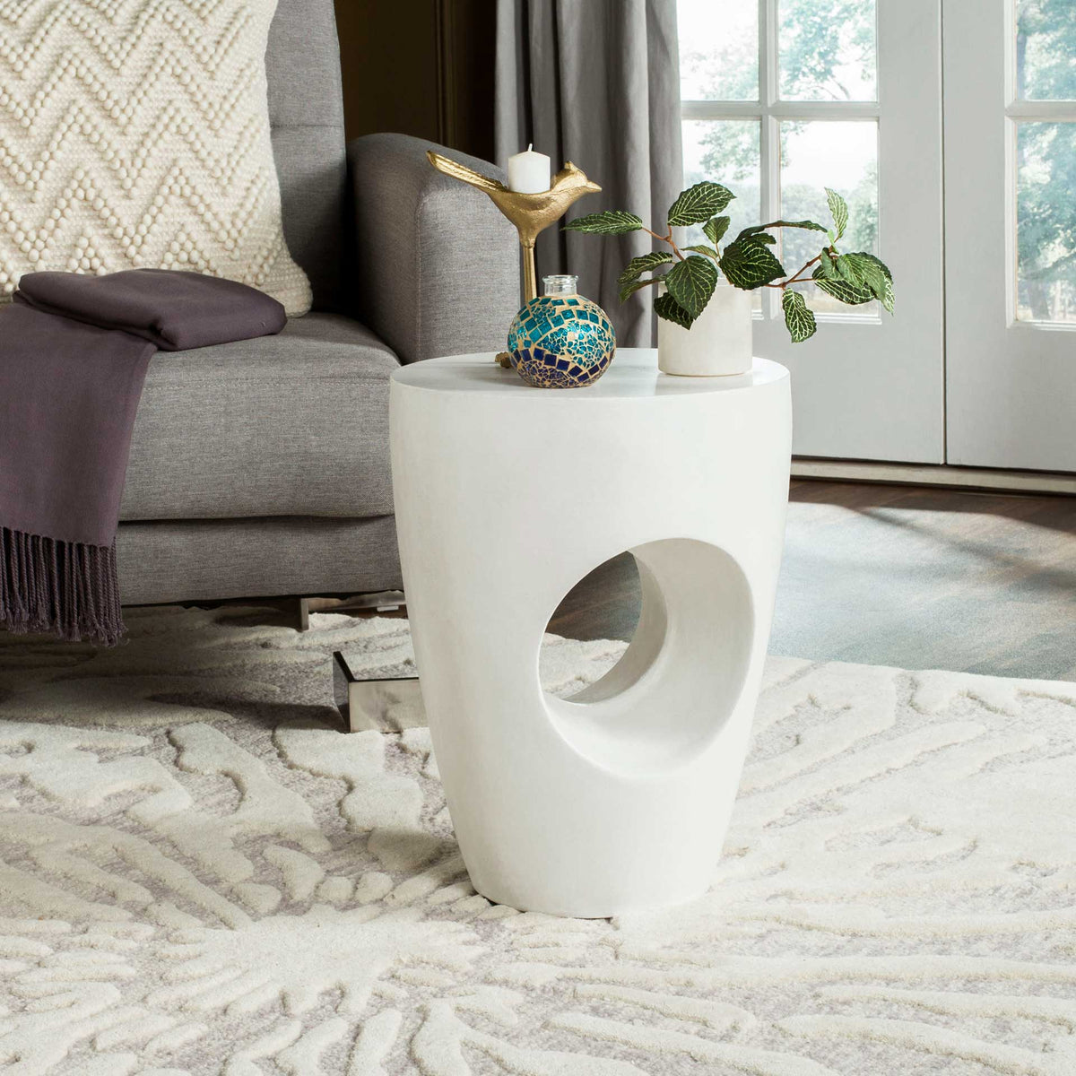 Ivory concrete accent table with a sculptural opening and a round top for plants and decor