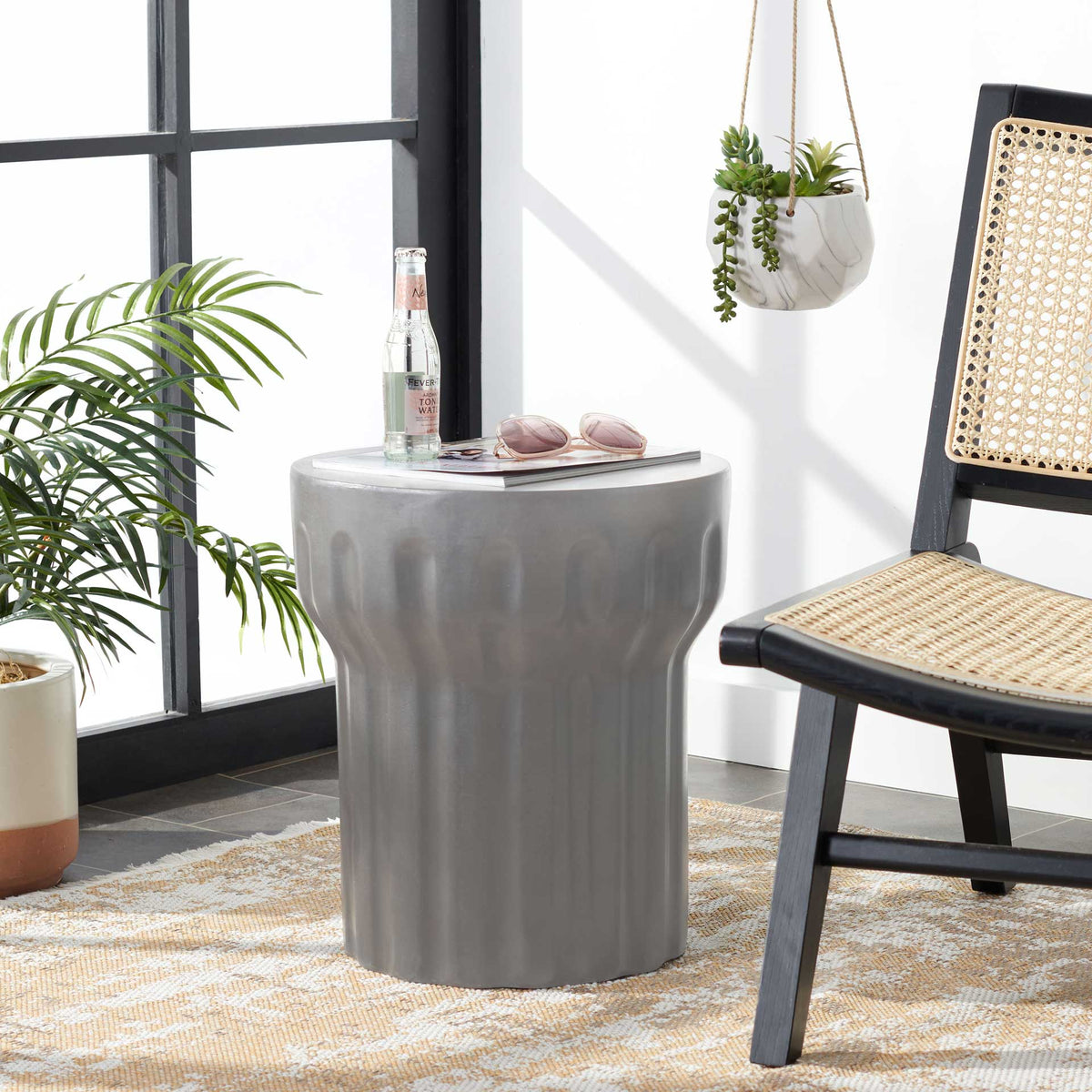Fluted dark gray accent table keeps drinks at hand beside a woven chair
