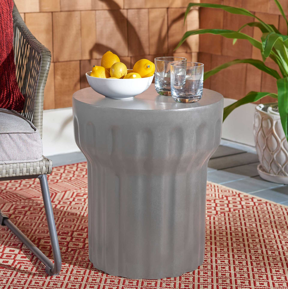 Sculptural gray concrete accent table holds fruit and drinks on a sunny patio