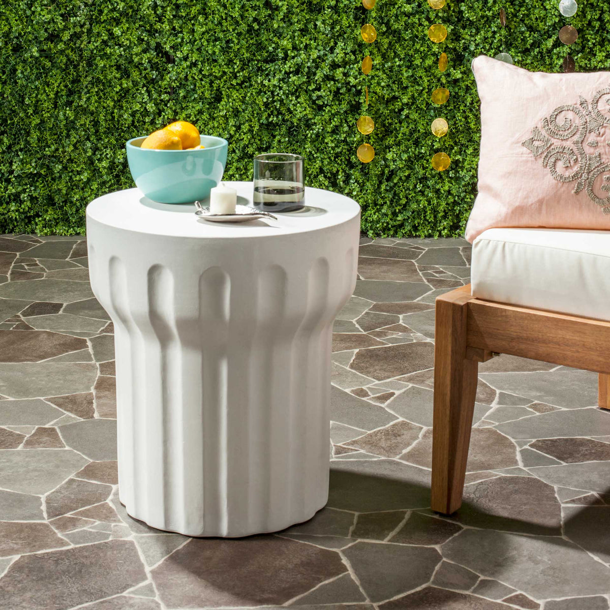 Fluted ivory accent table holds refreshments alongside cushioned outdoor seating