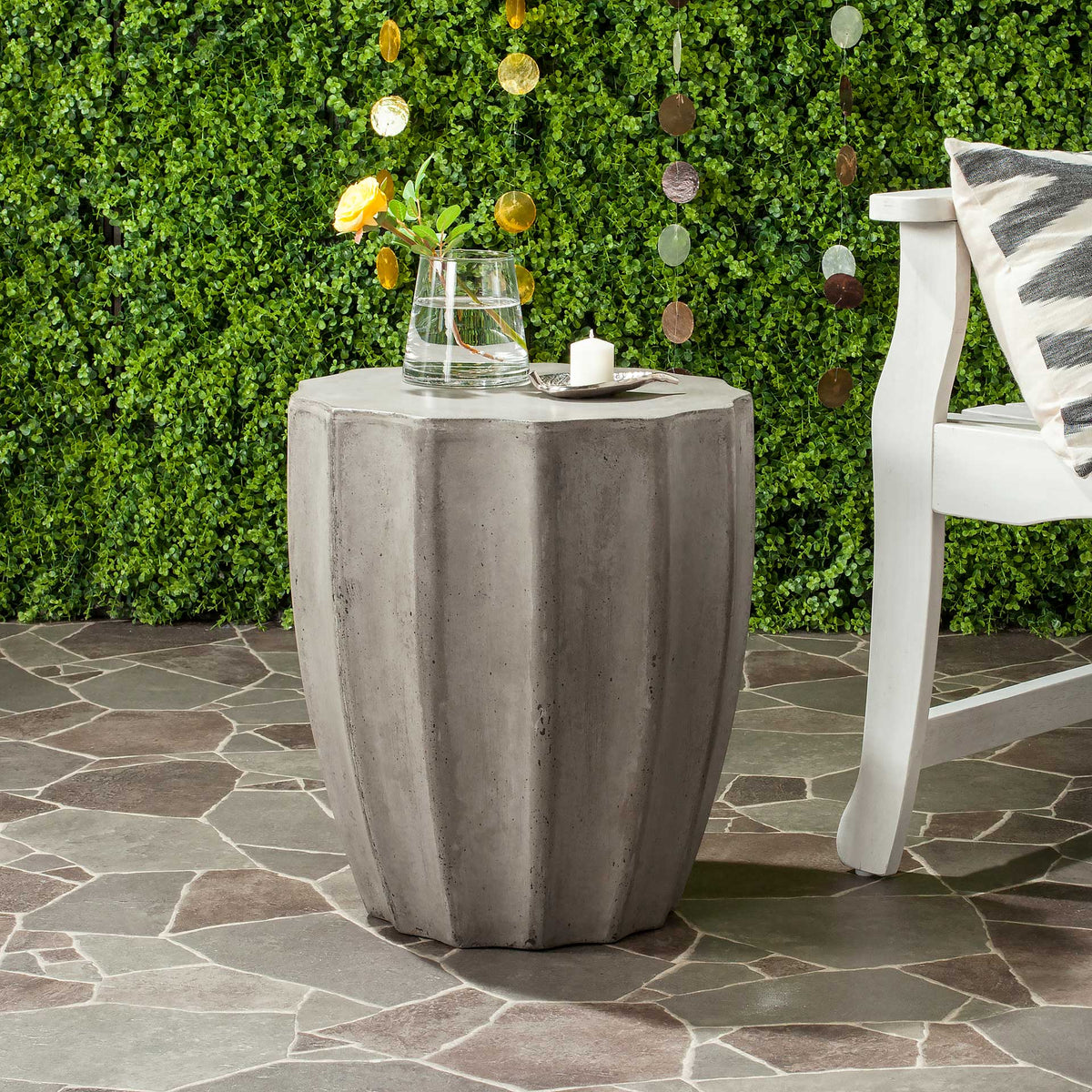 Fluted dark gray concrete table holds drinks and decor beside an outdoor chair