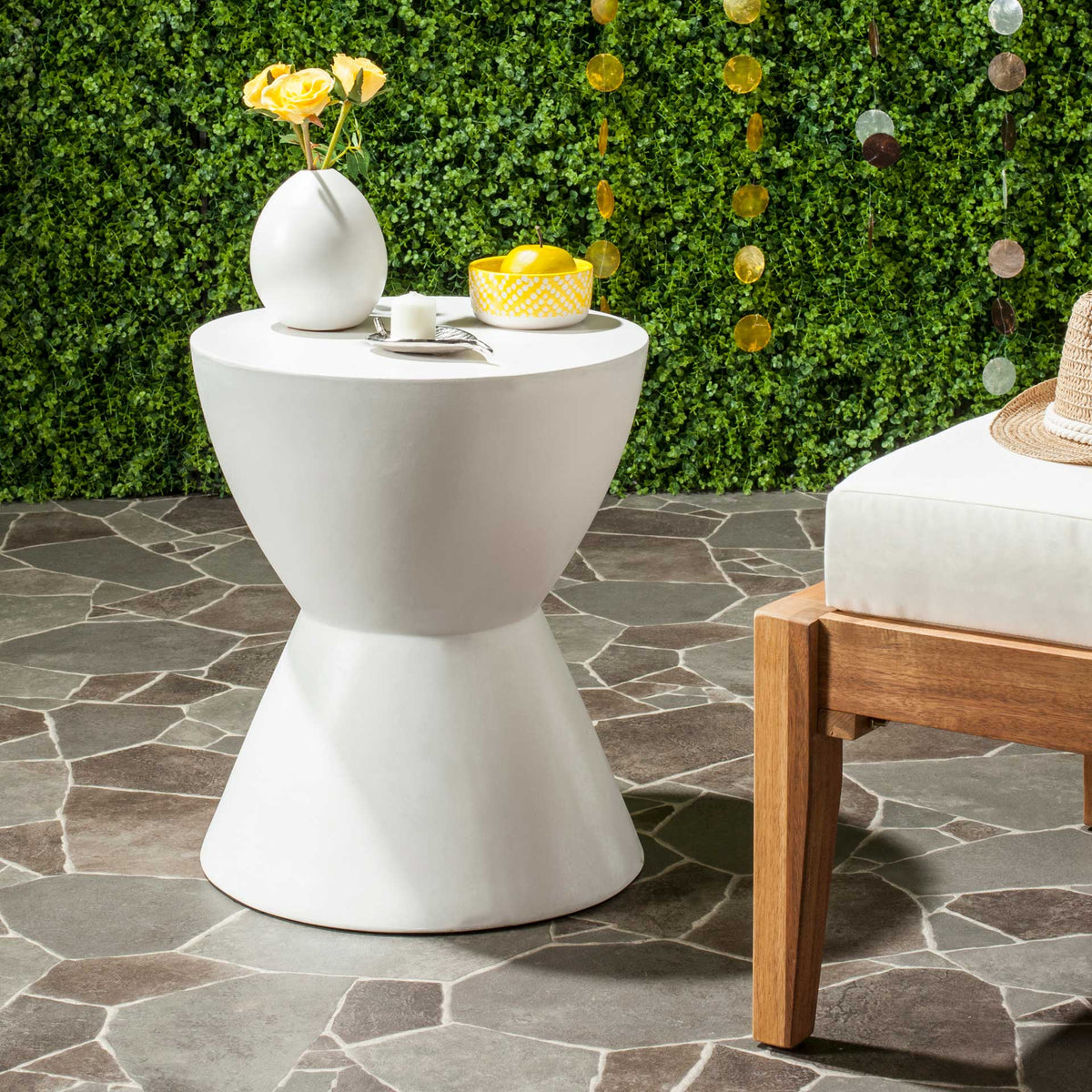 Ivory concrete accent table brings an hourglass shape and round top to a leafy patio