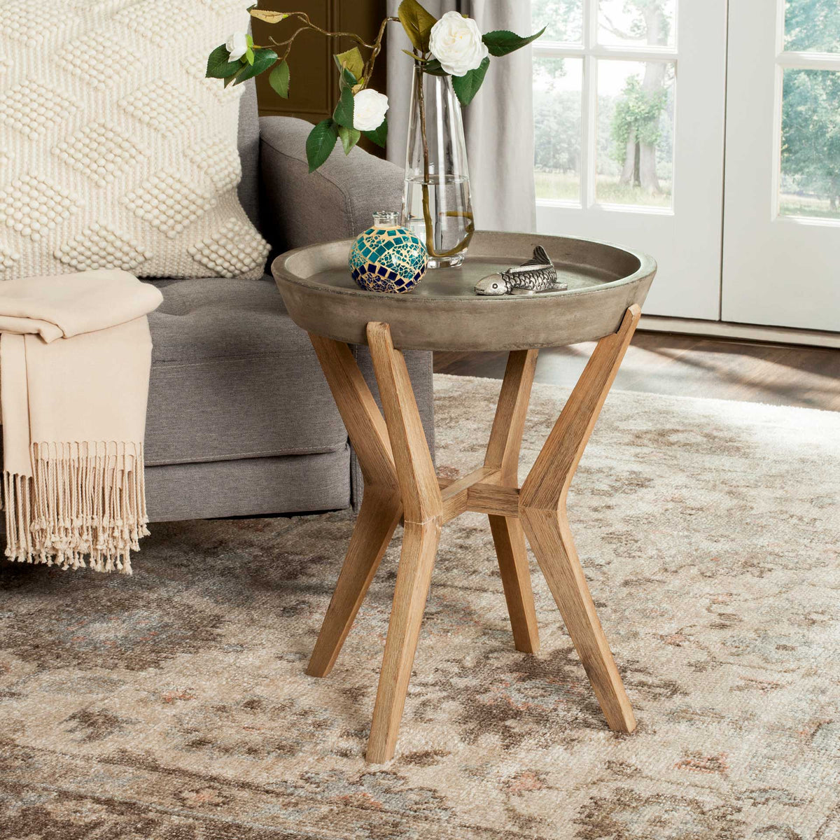 A round concrete tray top and sculptural wood base bring modern contrast to a cozy seating area.