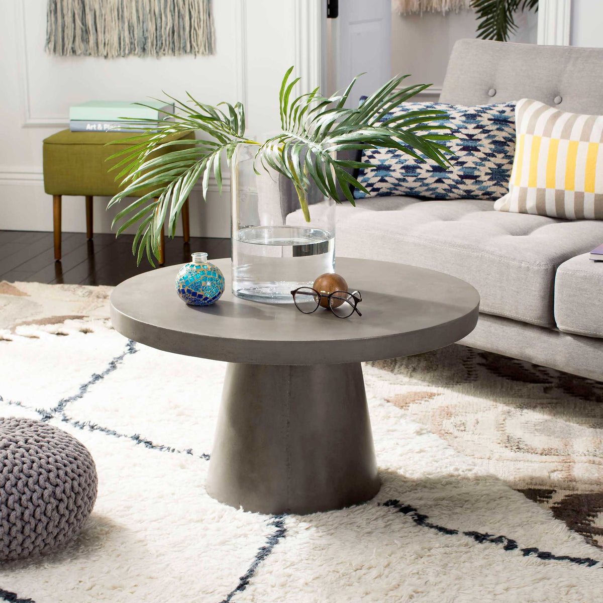 Dark gray round coffee table brings a generous surface and sturdy pedestal to a living room