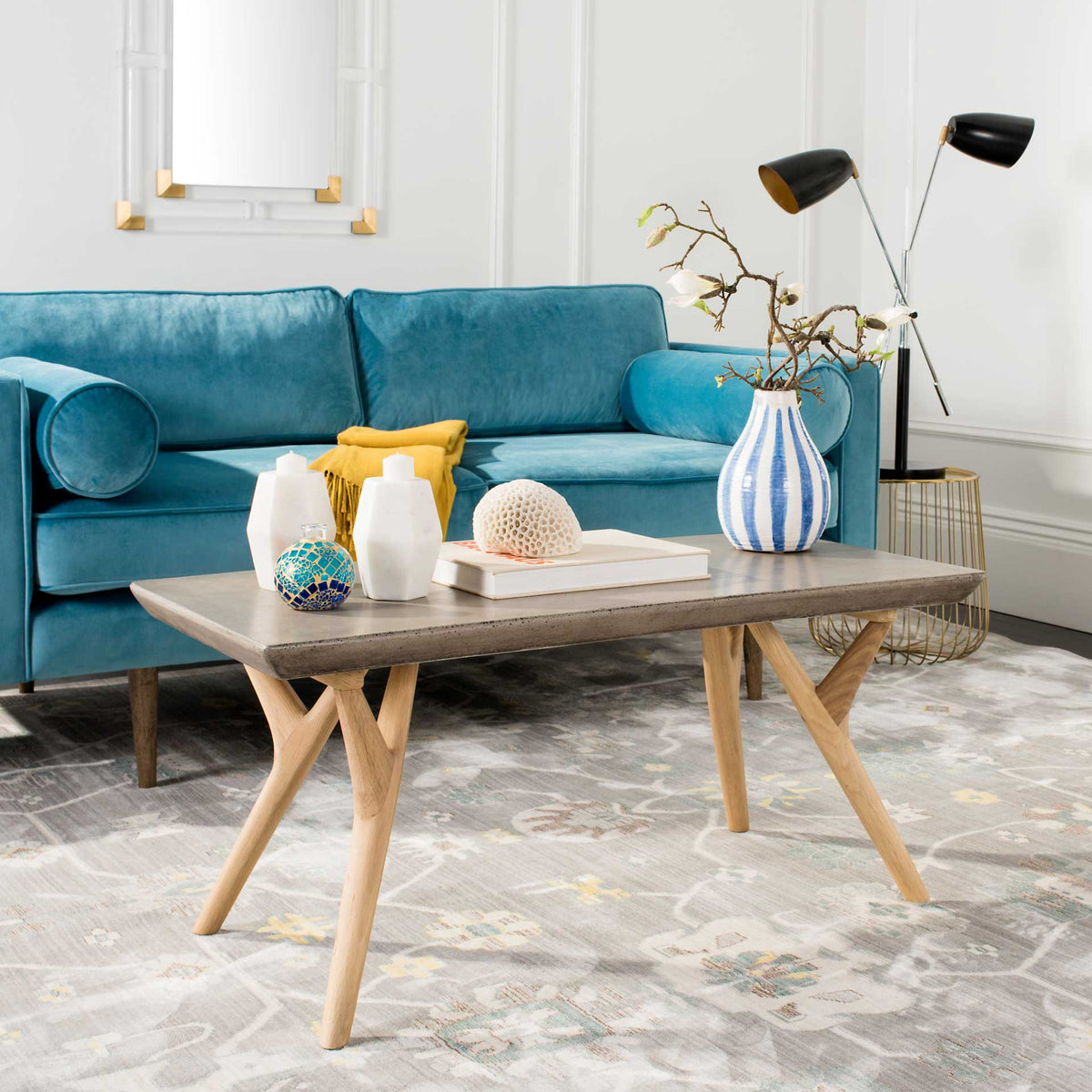 A concrete tabletop and angled oak legs add sculptural style beside a vibrant blue sofa.