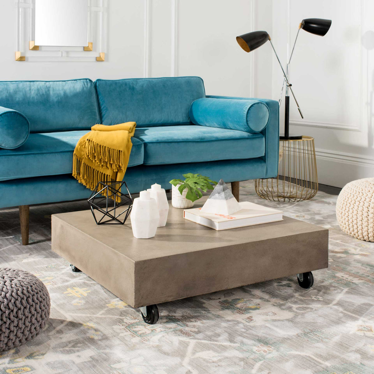 A low concrete coffee table on casters anchors a living room with understated industrial style.
