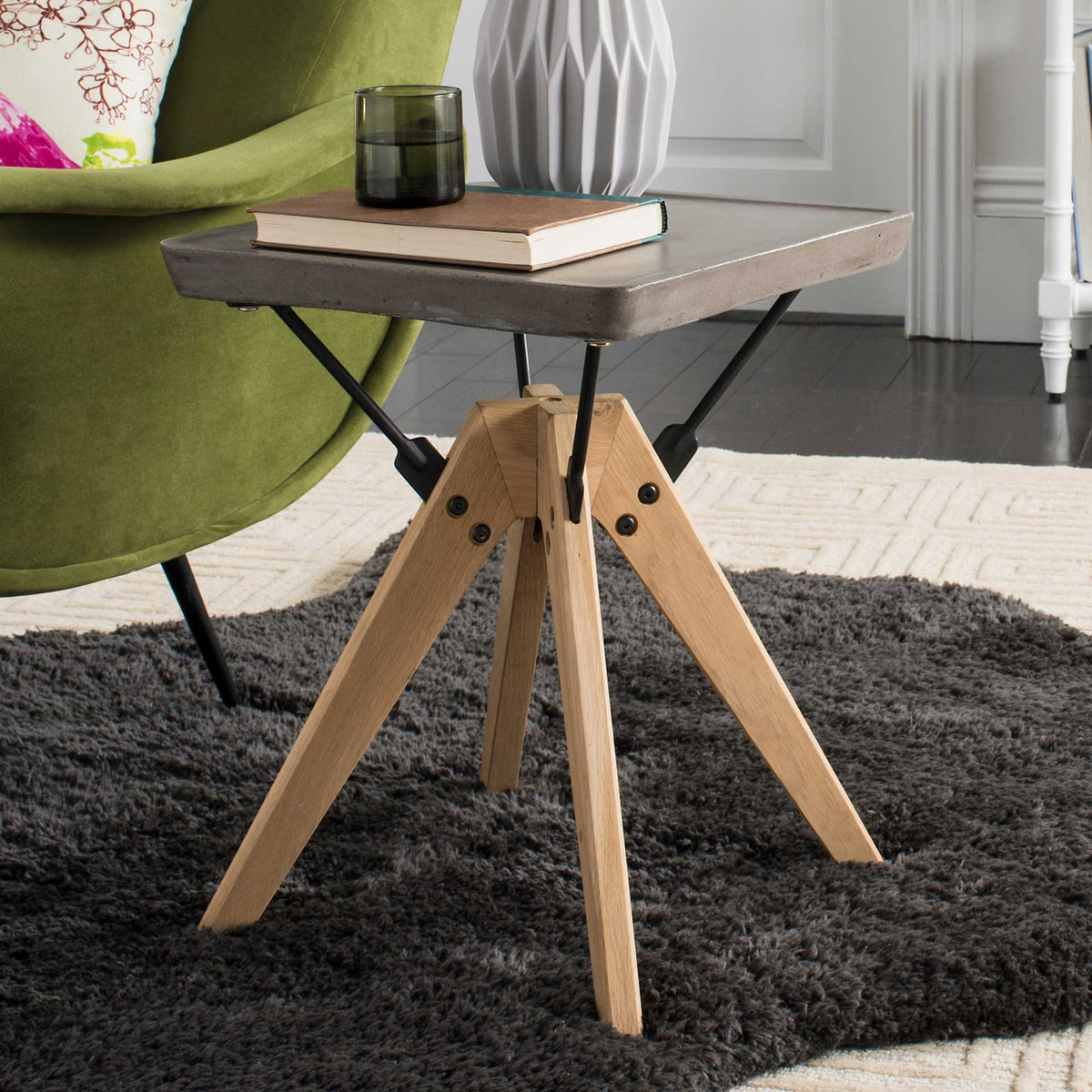 A dark gray concrete top holds books and decor above warm oak legs and slim black supports