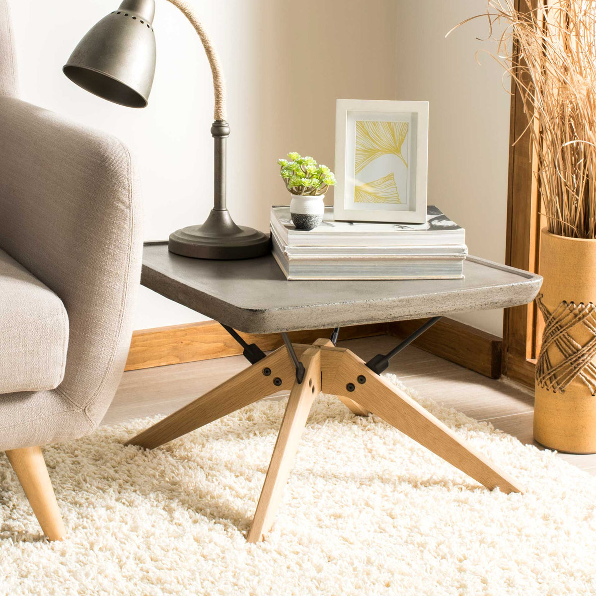 A dark gray concrete top and angled oak legs add modern contrast beside a soft upholstered sofa