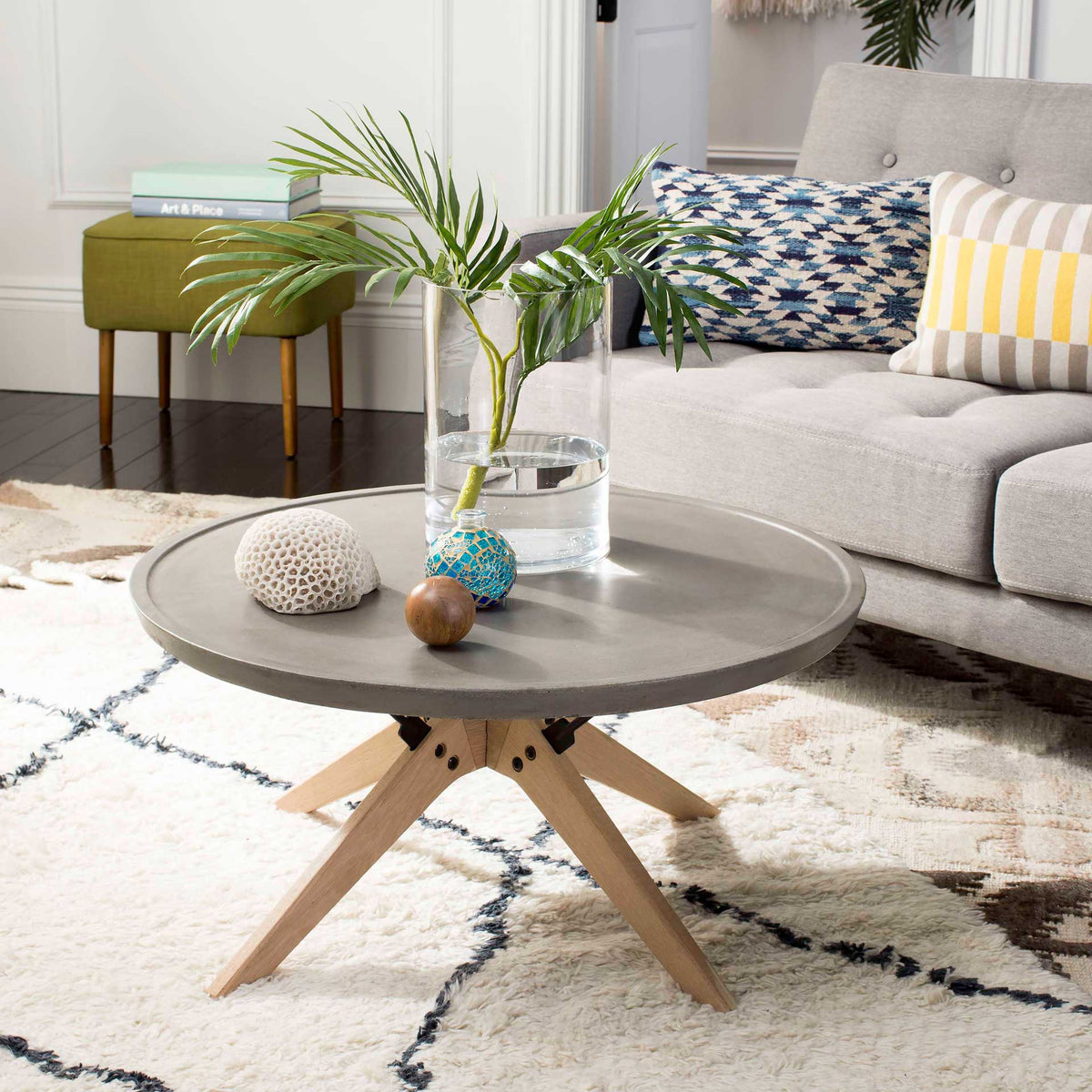 A low, round concrete coffee table with oak legs adds sculptural contrast to a cozy living area.