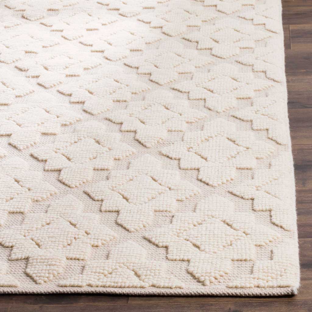 Raised geometric shapes add dimension to the ivory rug, with a neatly finished edge