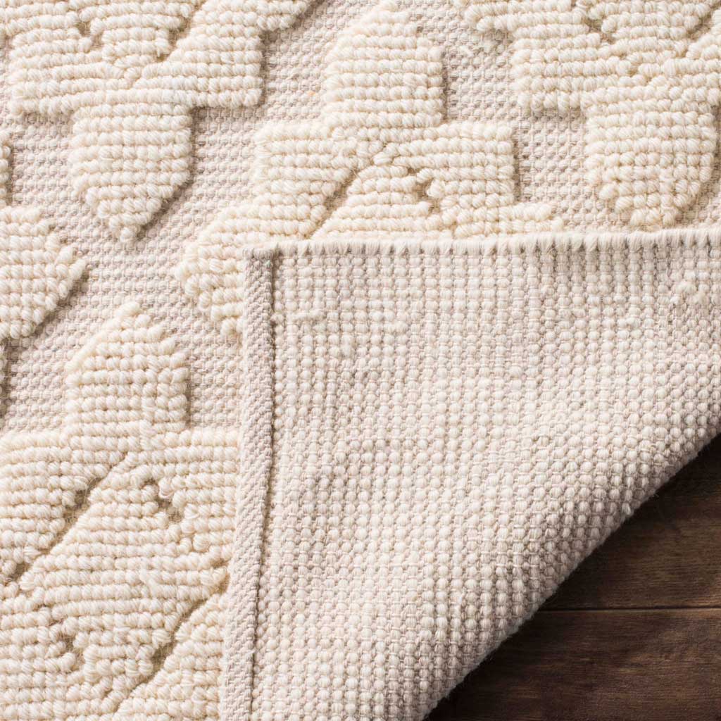 Soft ivory geometric pile contrasts with the rug's tightly woven underside