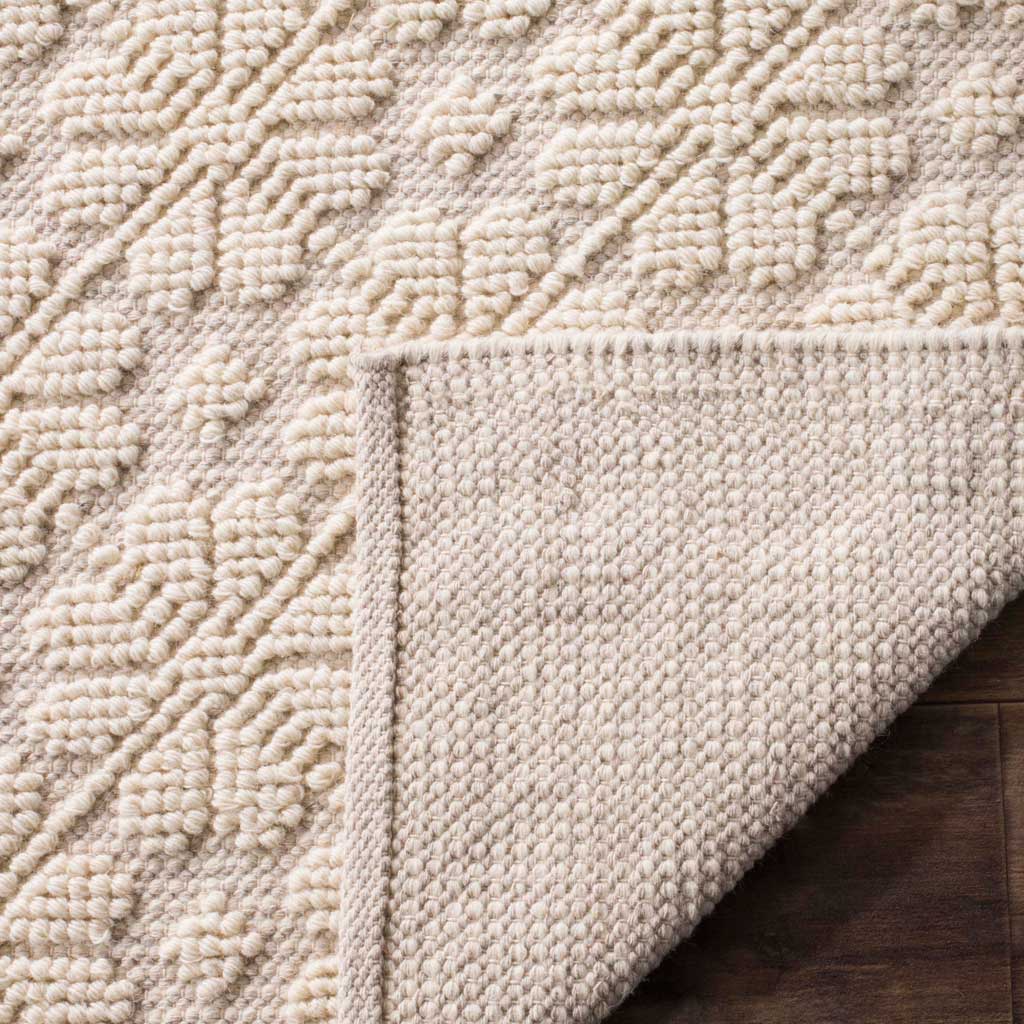 A textured woven backing complements the ivory rug's dimensional geometric design