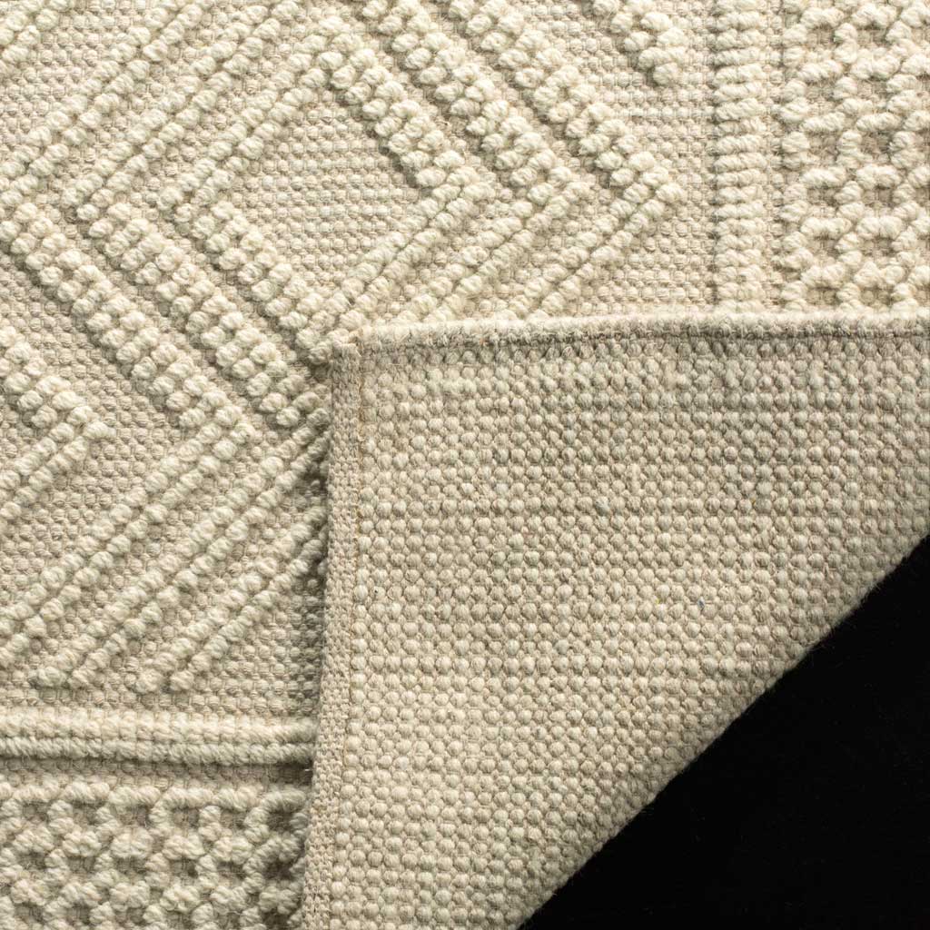 A woven cotton backing supports the ivory rug's raised geometric texture