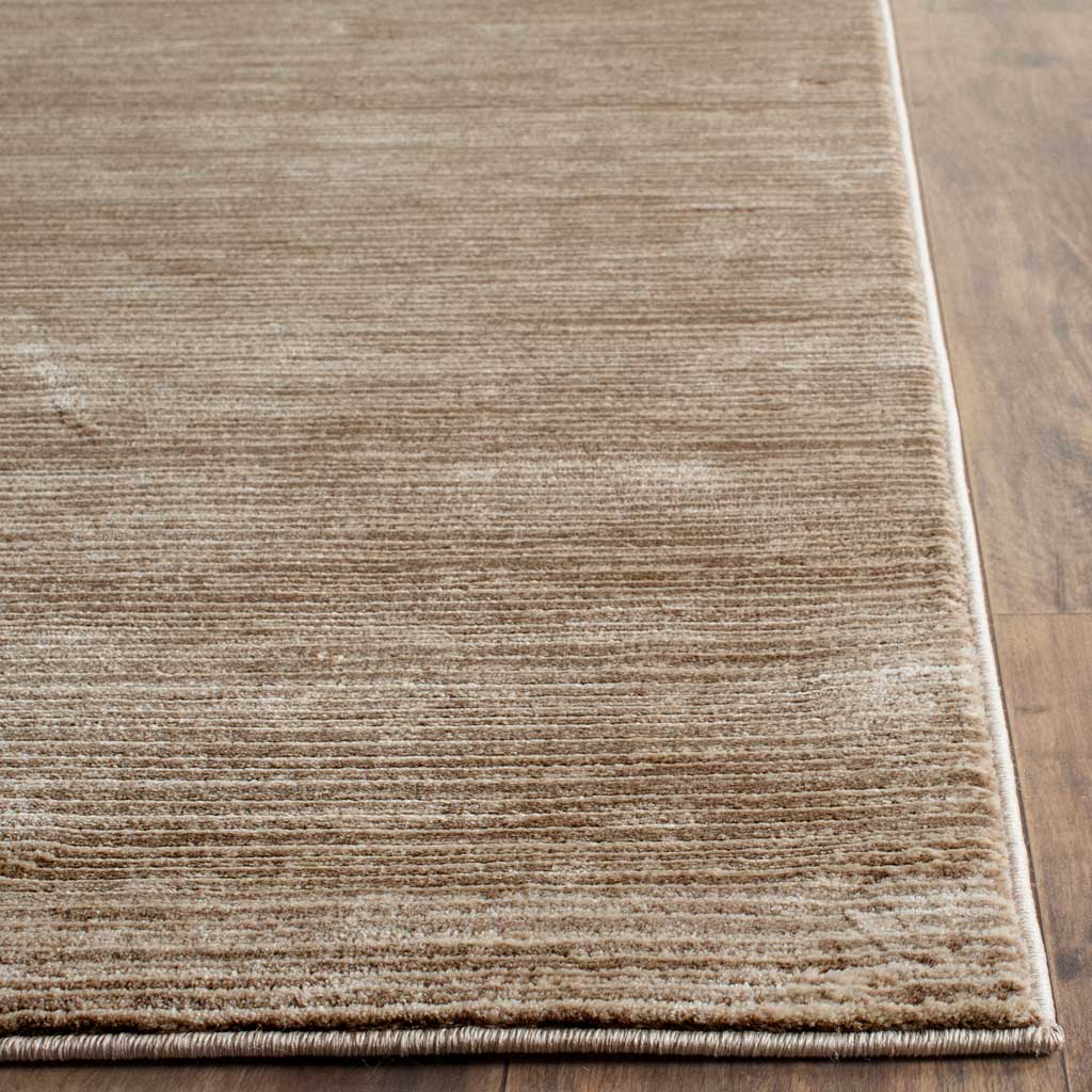 Bound edges finish the light brown rug's dense, softly striated pile.