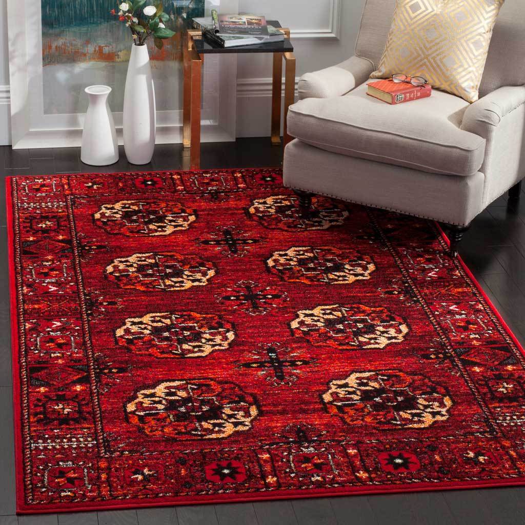 Red medallion rug adds dramatic color beneath a pale upholstered armchair