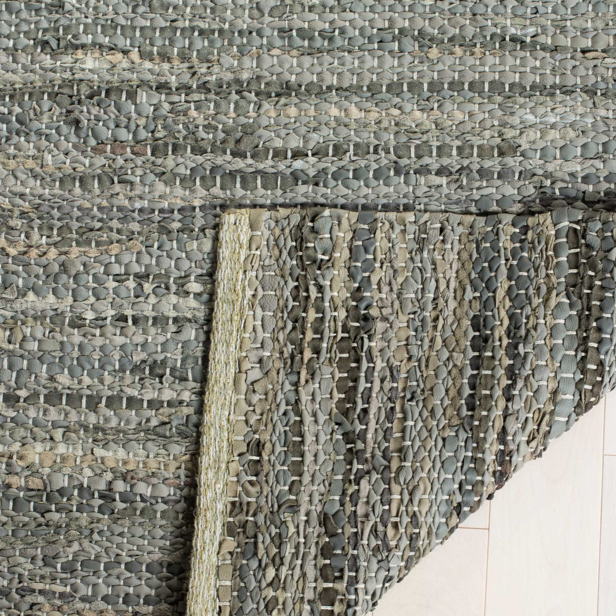 Folded underside displays the rug's woven gray leather and cotton fibers