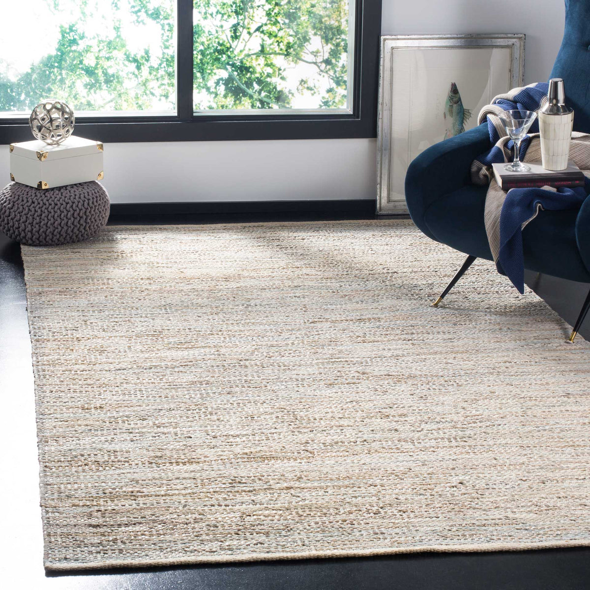 Soft beige striped rug adds warmth beneath a deep blue lounge chair