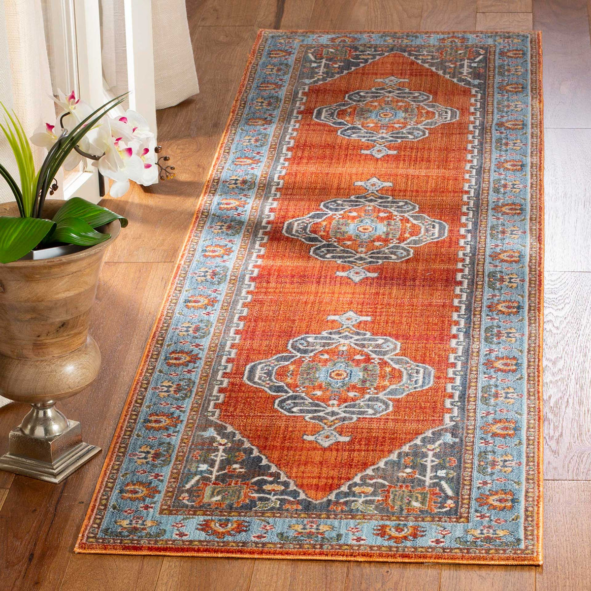 Warm rust runner highlights ornate blue-gray medallions and a contrasting blue border
