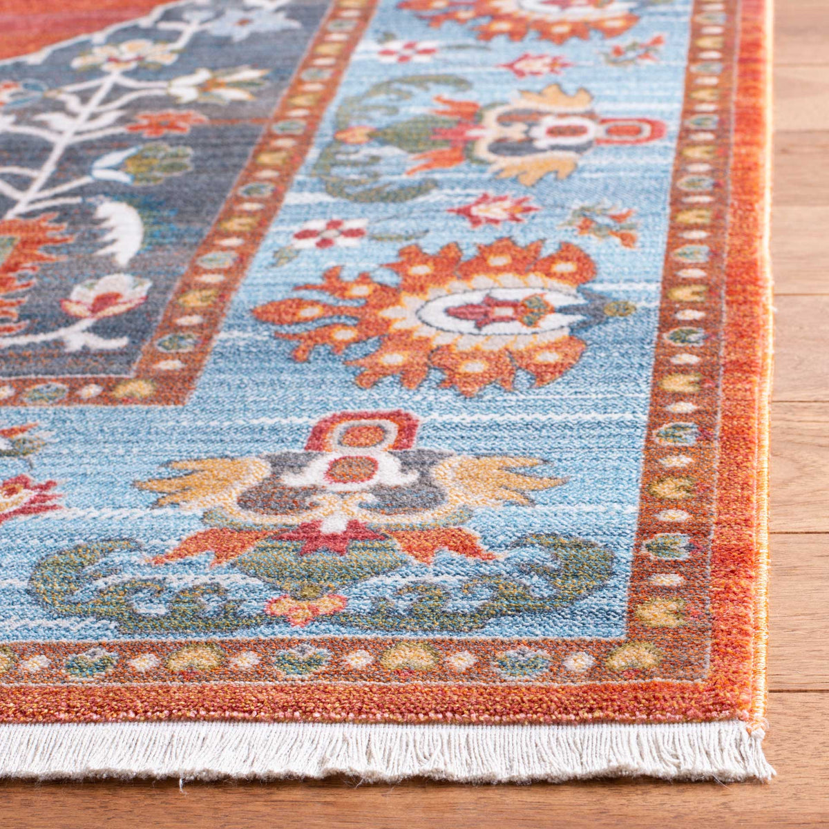 White fringe edges the rug's vivid blue floral and rust patterned border