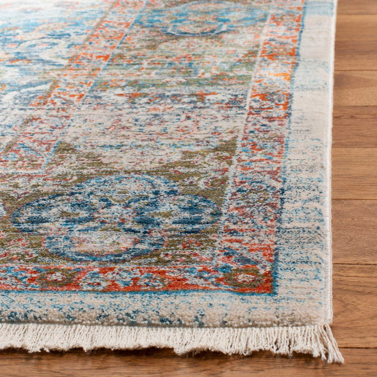 Cream fringe softens the blue and coral floral border of the beige rug