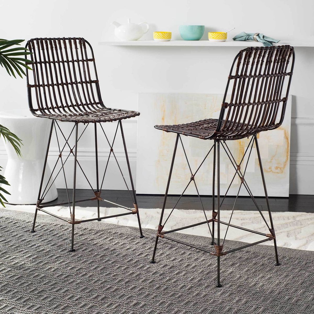 Two brown woven rattan counter stools combine gently curved seats with lean black metal legs